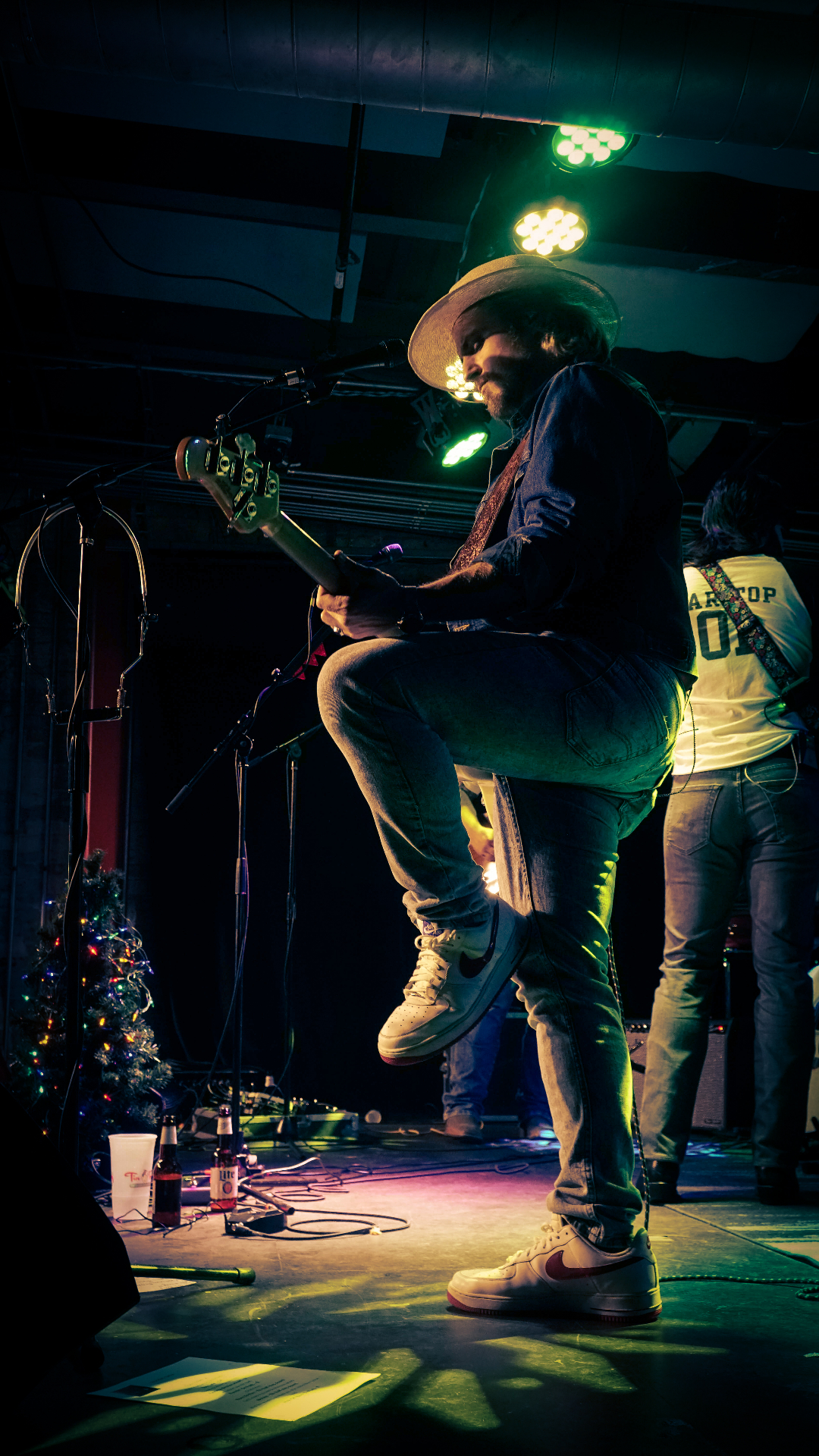 Bass guitarist performing on stage with dramatic atmospheric lighting and stage effects