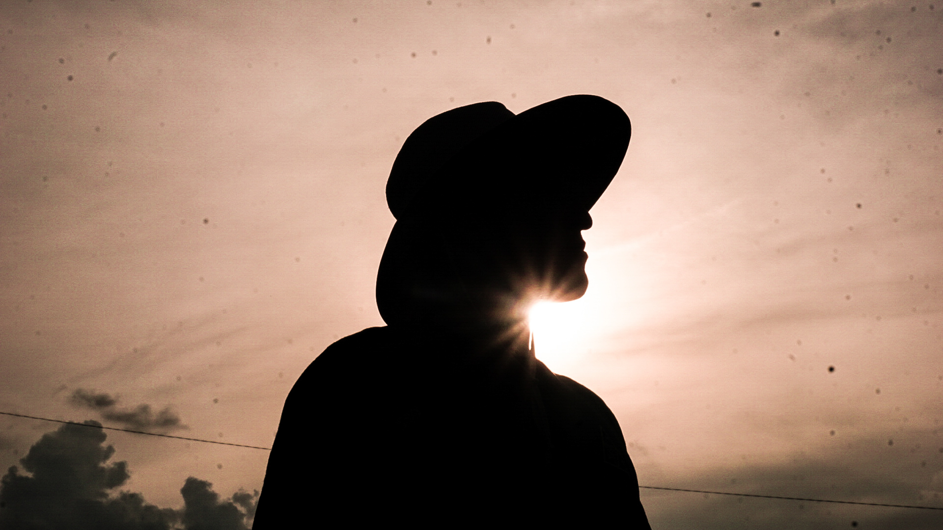Artistic silhouette portrait with dramatic sun flare and warm sunset colors
