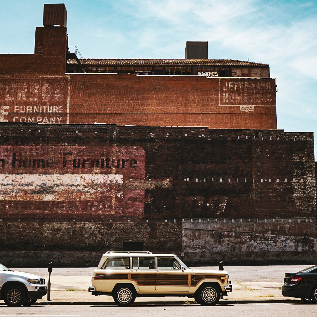 Vintage van parked against weathered brick wall with painted signage creating urban atmosphere