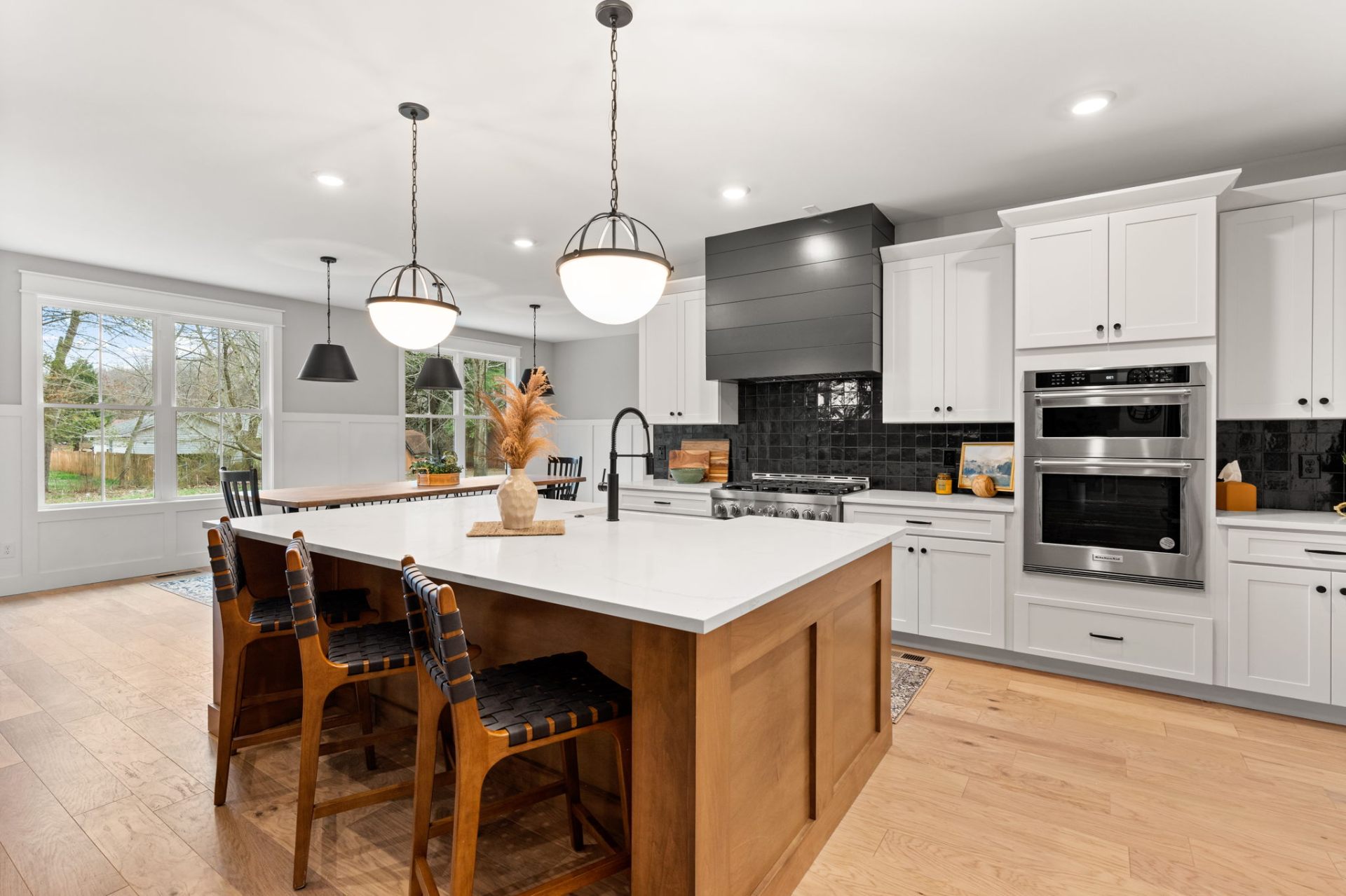 Stunning kitchen featuring white cabinets, natural wood island and black tile backsplash