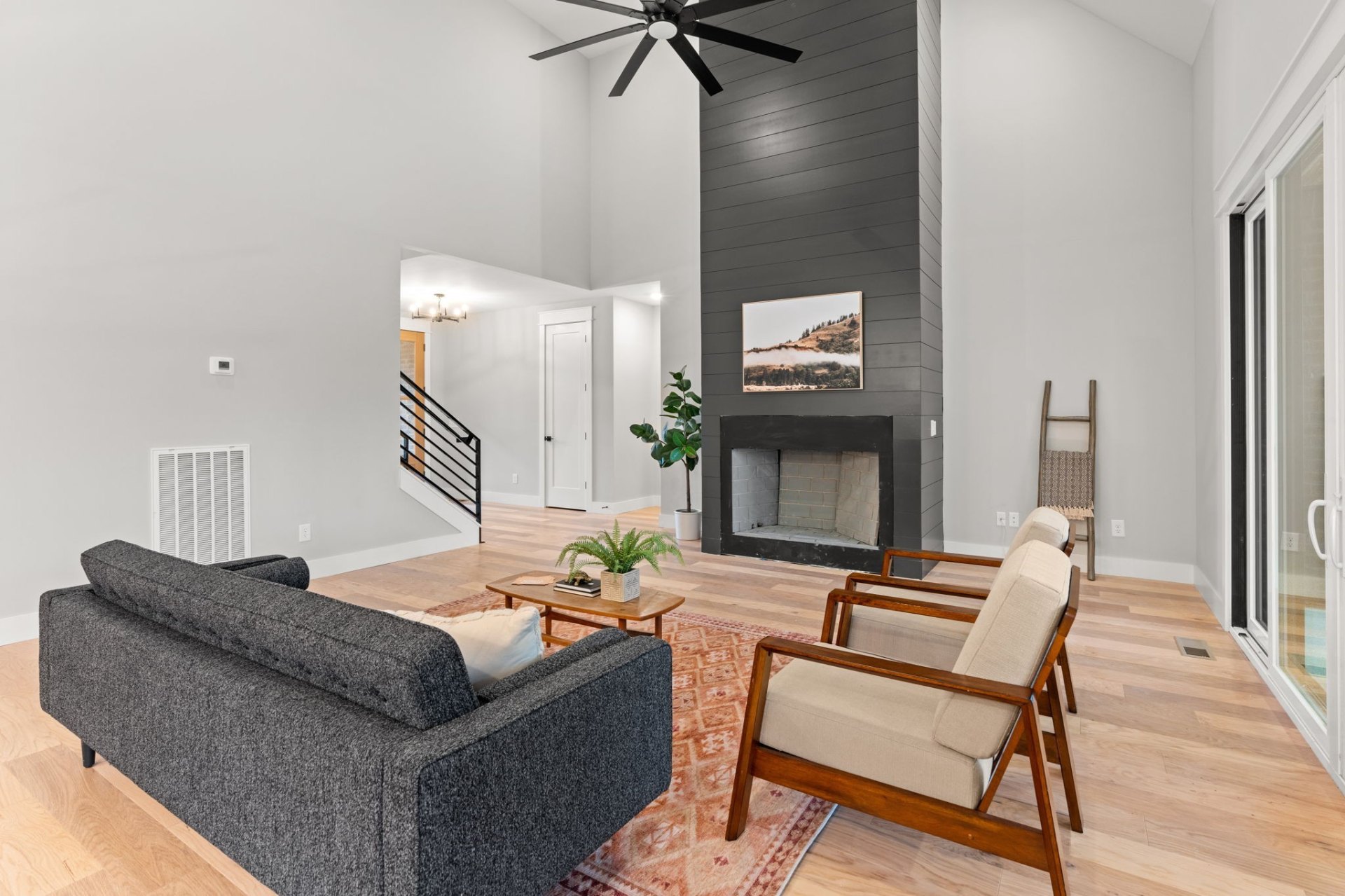 Modern living space with dark shiplap fireplace wall, mid-century furniture and vaulted ceiling