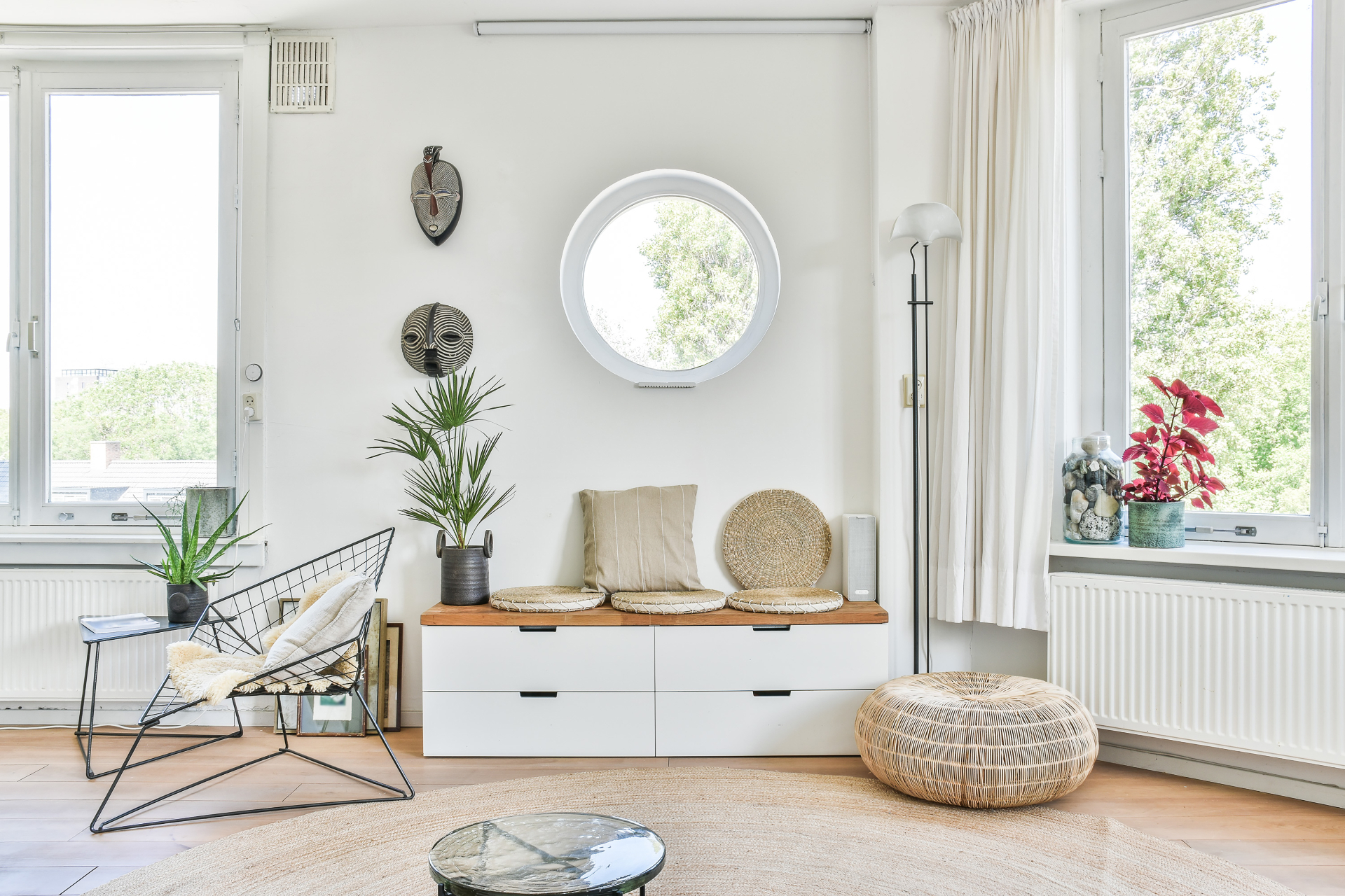 Bright minimalist living room with round window and wire frame accent chair
