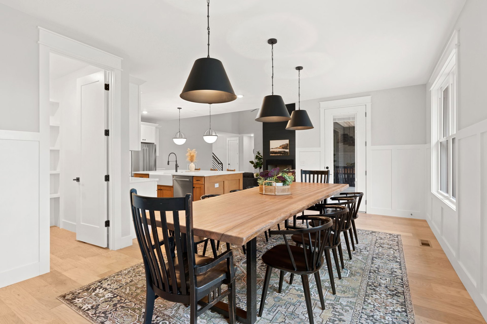 Spacious dining area with live-edge table, black pendant lights and kitchen view