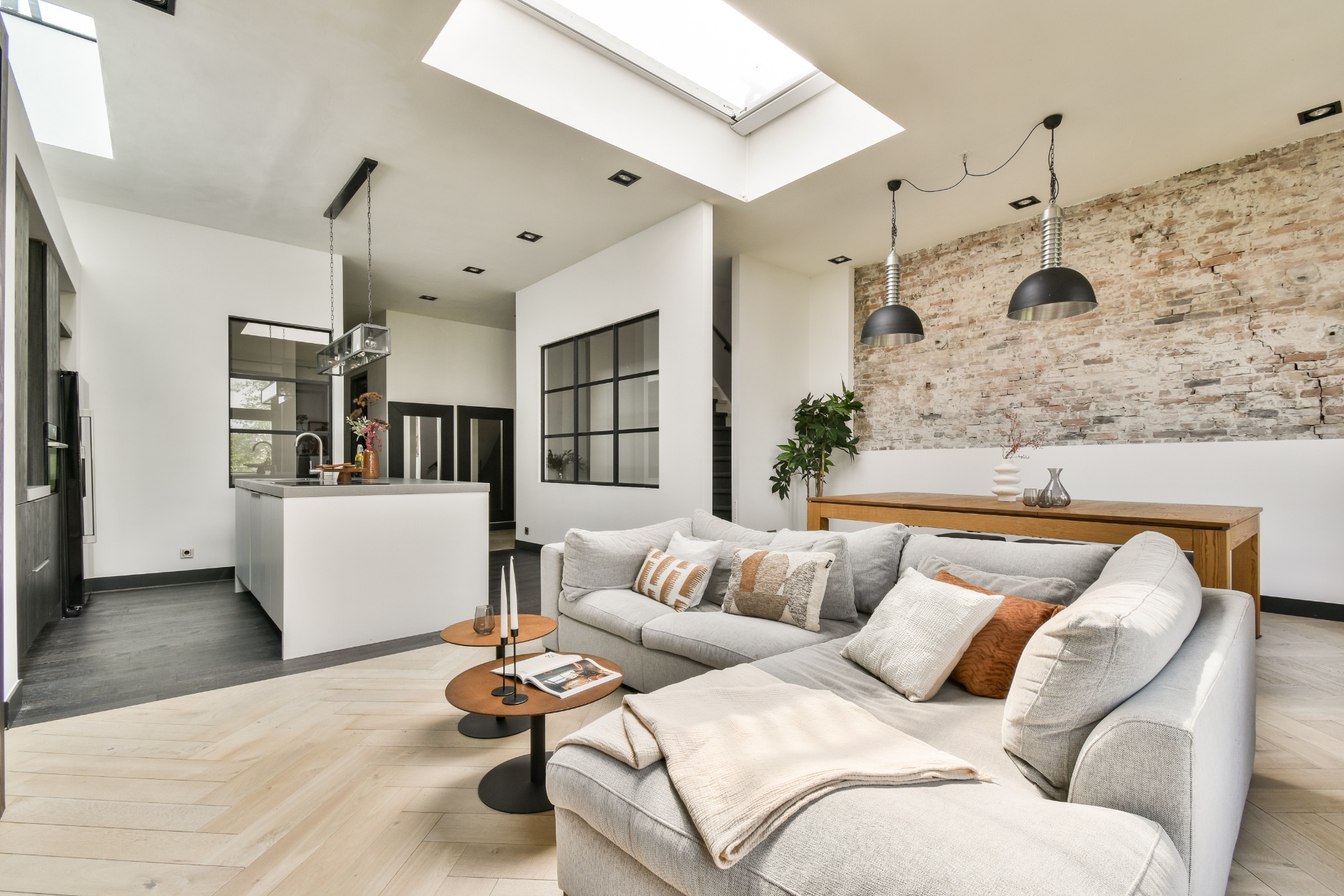 Contemporary loft space with exposed brick wall, sectional sofa and modern kitchen