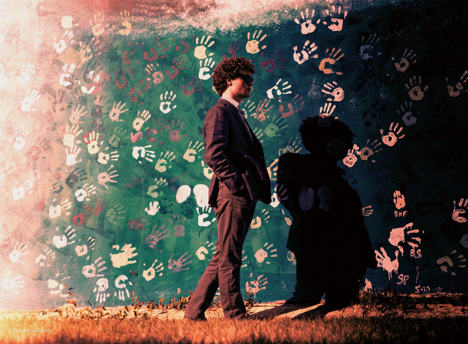 Creative artistic portrait of person in formal suit against vibrant colorful handprint mural wall