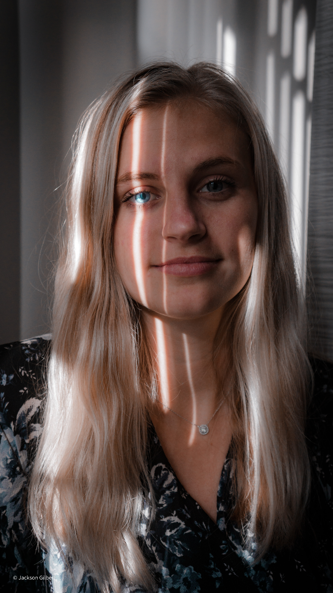 Professional portrait of blonde woman with dramatic window lighting creating beautiful shadows