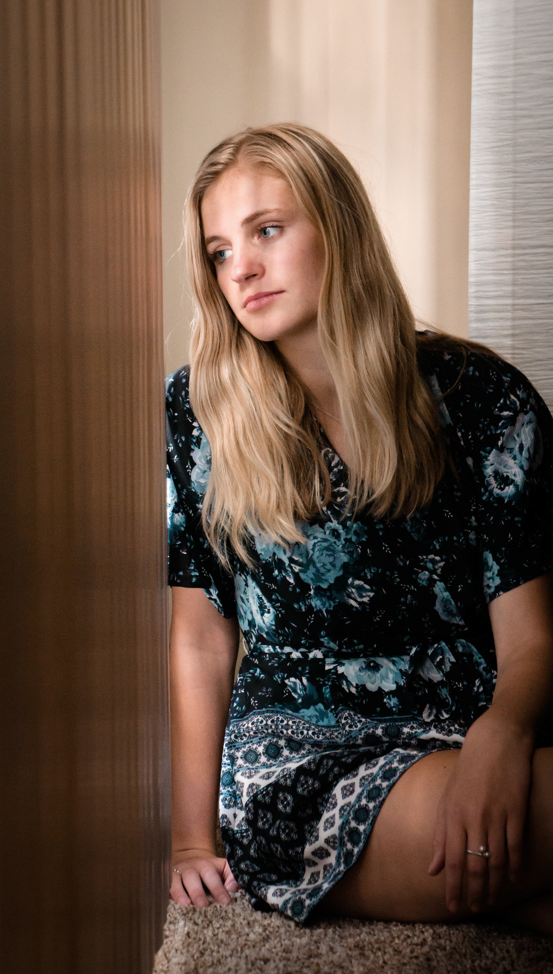 Beautiful indoor portrait of young woman with natural window lighting and floral dress