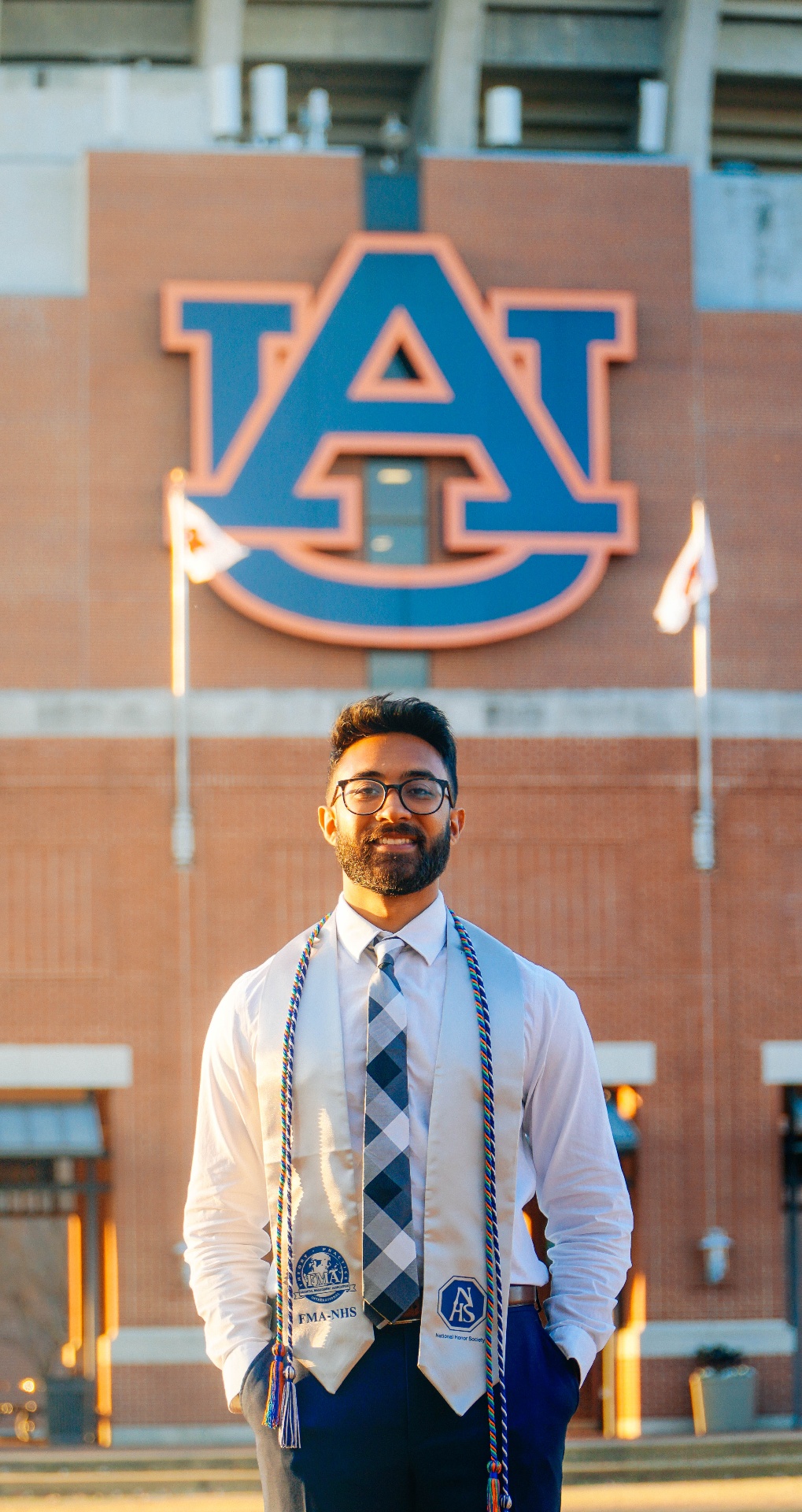 Formal graduation portrait with honors cords at Auburn University campus entrance