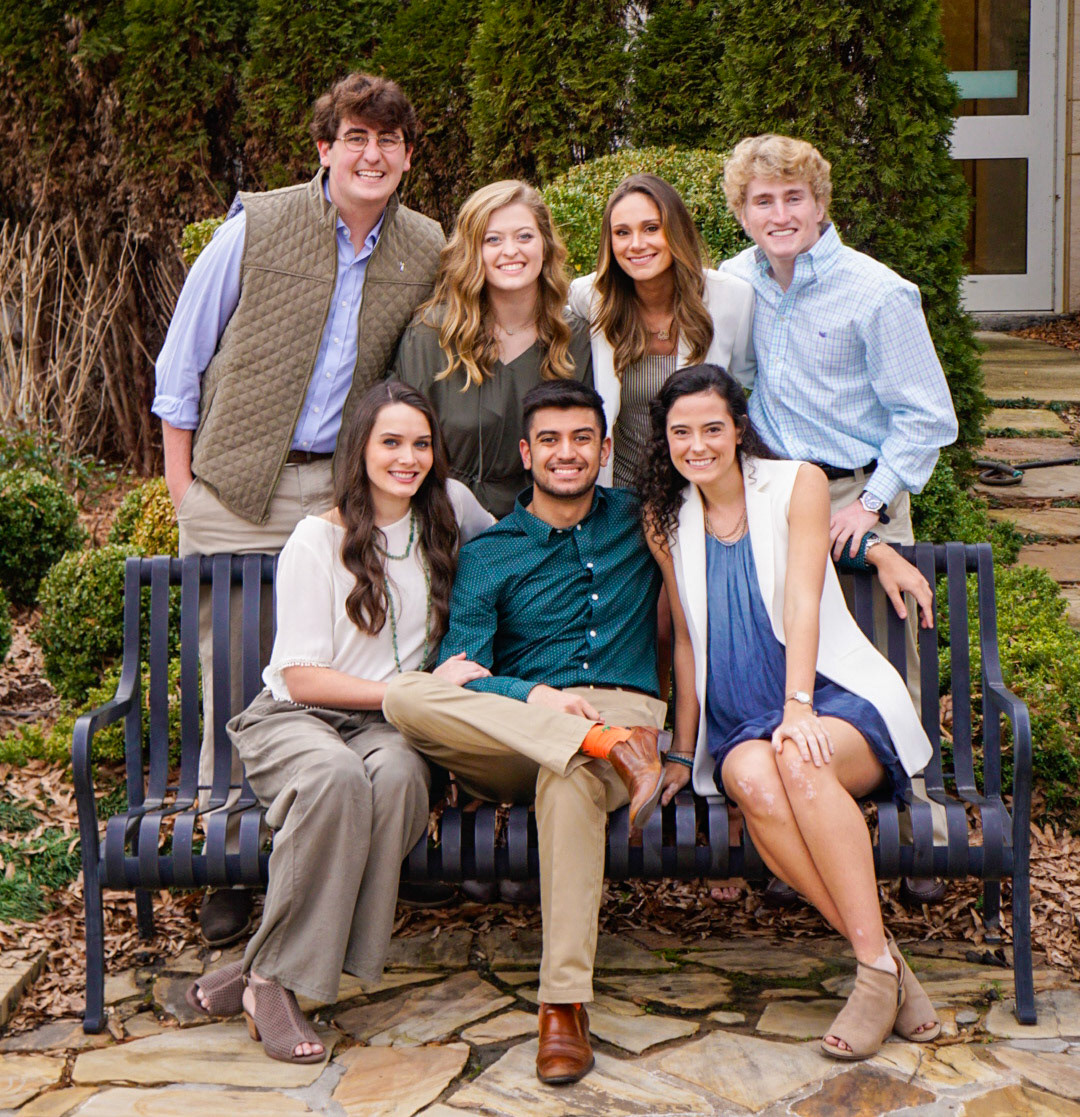 Elegant formal group portrait of friends in coordinated outfits on outdoor bench